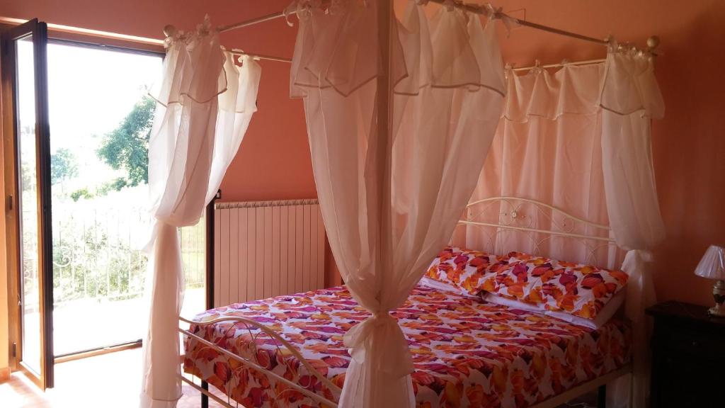 una camera da letto con un letto con tende e una finestra di Domus Quarticelli Costa dei Trabocchi a Torino di Sangro