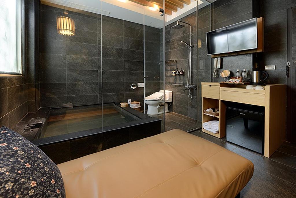 a bathroom with a tub and a sink and a television at Yunoyado Onsen Hot Spring Hotel -Xinyi Branch in Jiaoxi
