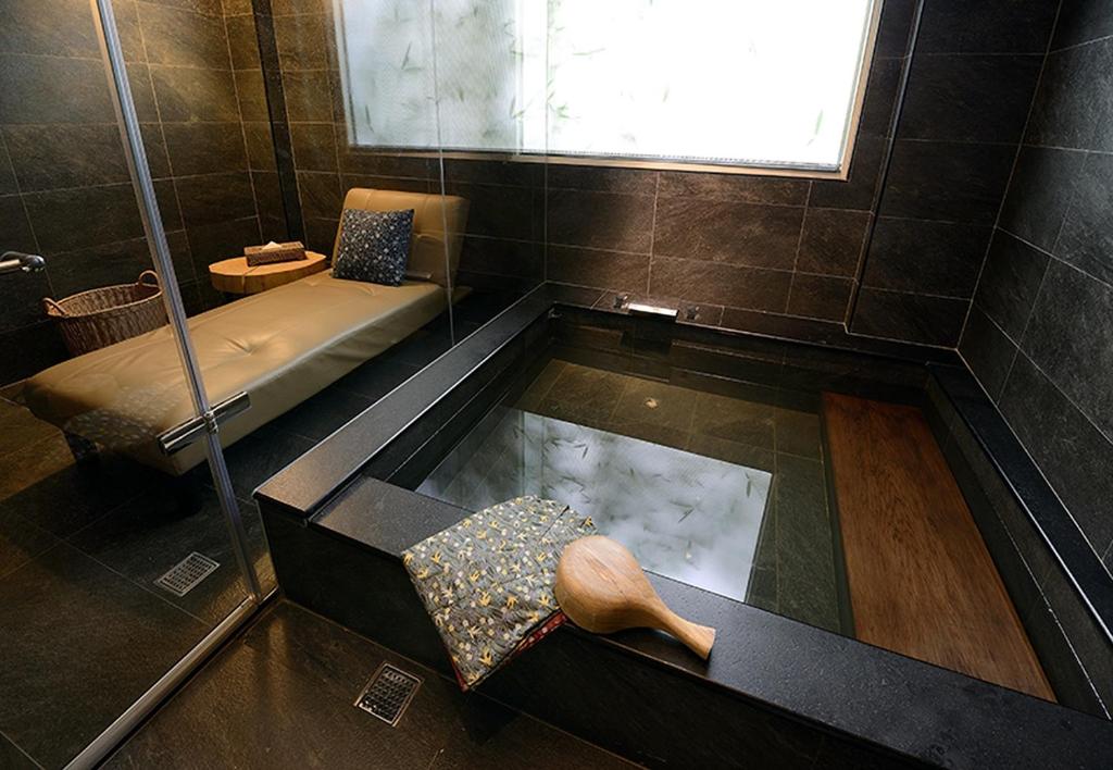 a bath room with a bath tub with a bench and aumedumedumedumed at Yunoyado Onsen Hot Spring Hotel -Xinyi Branch in Jiaoxi