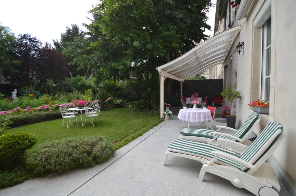 eine Terrasse mit Stühlen, einem Tisch und einem Garten in der Unterkunft Chambre d'hôtes à TOUL centre ville avec parking privé in Toul