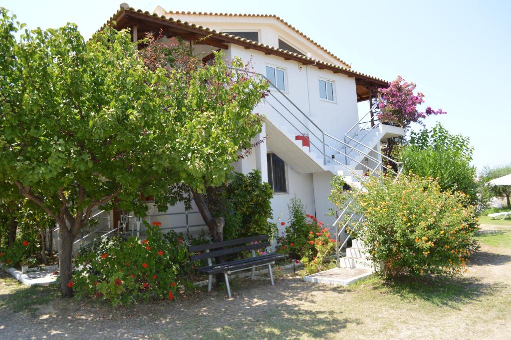 un banc devant une maison plantée d'arbres et de fleurs dans l'établissement Theodore Apartments, à Zakharo