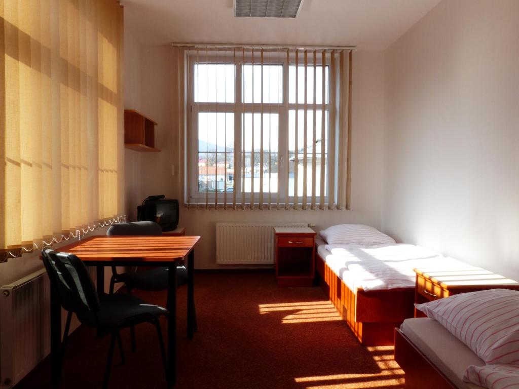 ヴルフラビーにあるUbytovani Ricoのベッド2台、テーブル、デスクが備わる客室です。