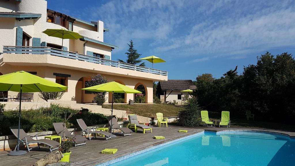 einen Pool mit Stühlen und Sonnenschirmen neben einem Gebäude in der Unterkunft Le Mas de Chartreuse in Miribel-les-Échelles