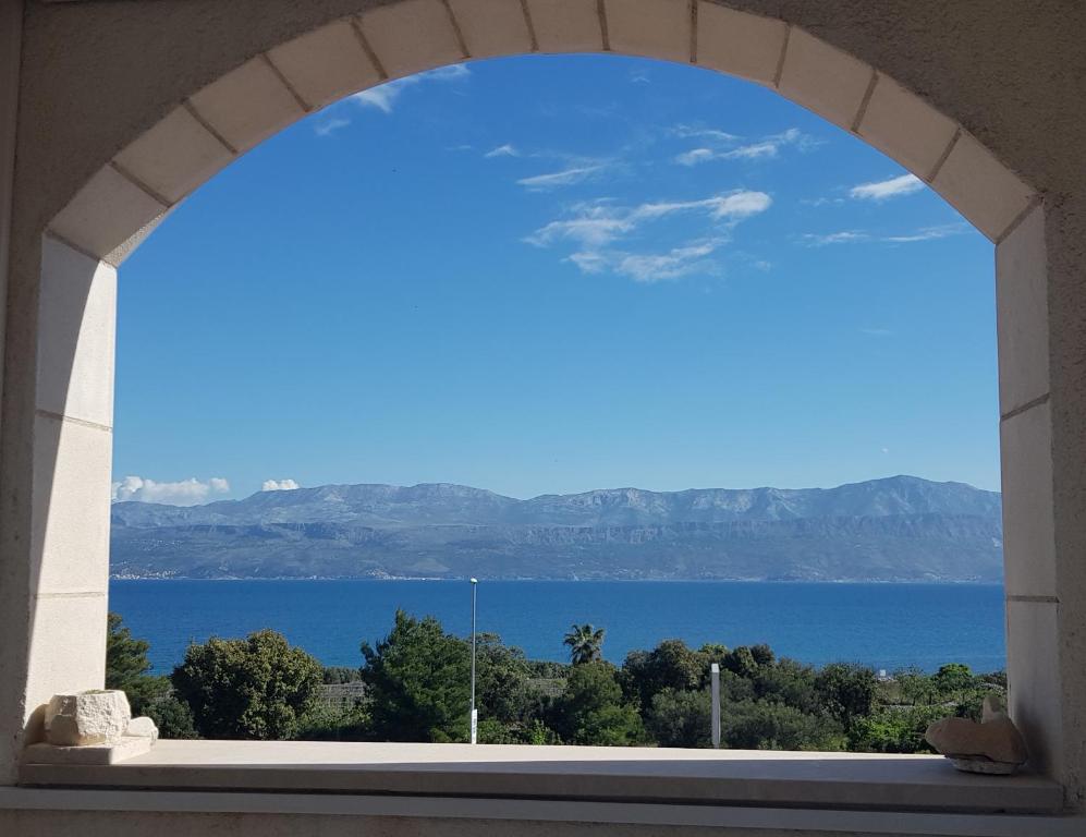 ein Fenster mit Blick auf das Wasser und die Berge in der Unterkunft Apartment Frida in Supetar
