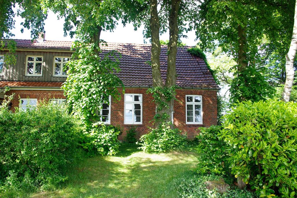 ein rotes Backsteinhaus mit Bäumen davor in der Unterkunft Alte Schule Osteroden in Merzen