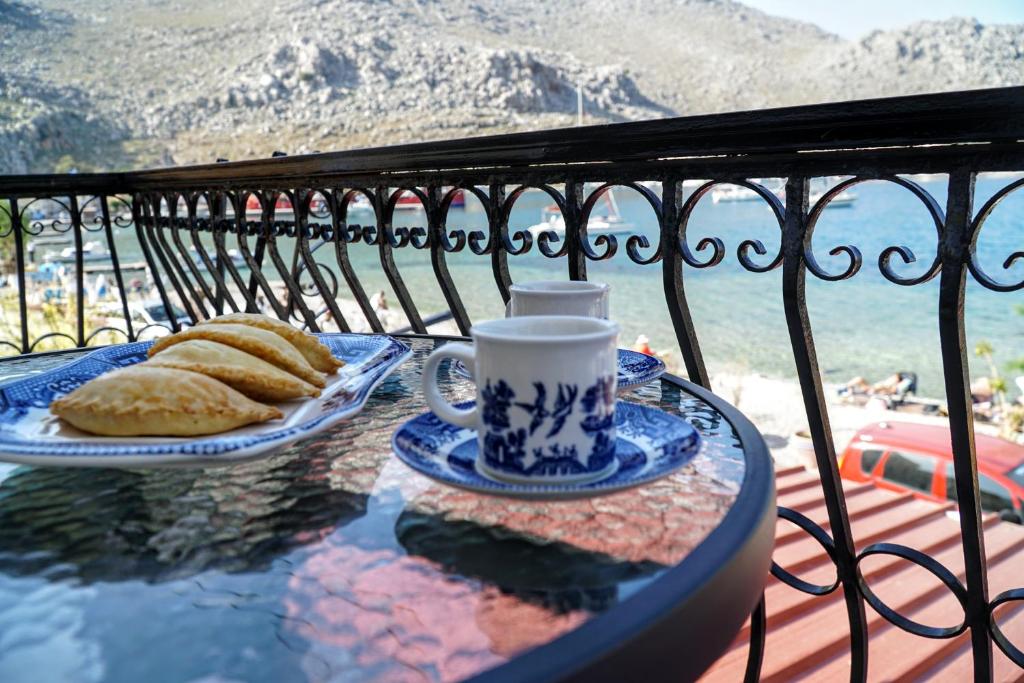 a table with a cup of coffee and bread on a balcony at Korali in Symi