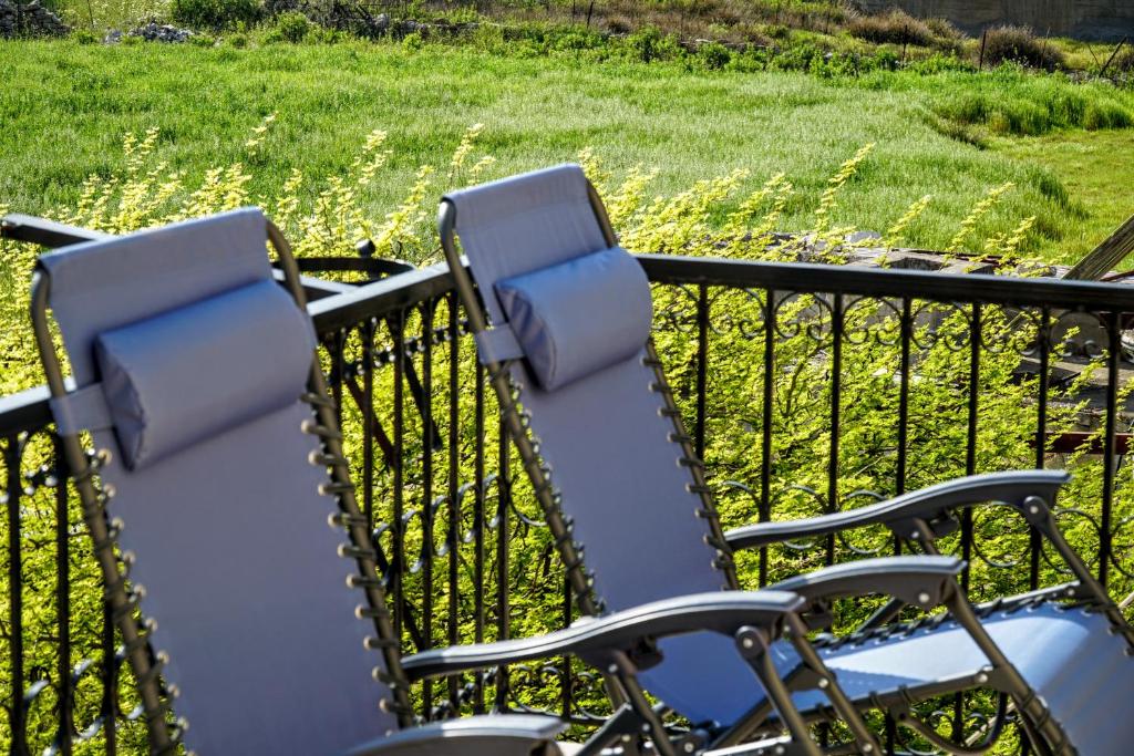 two chairs on a balcony with a field of grass at Korali in Symi