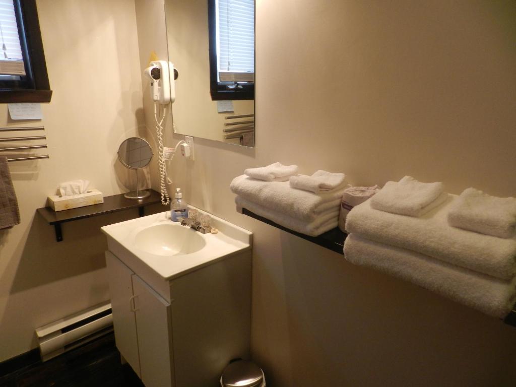La salle de bains est pourvue d'un lavabo, d'un miroir et de serviettes. dans l'établissement Maison Chez Laurent, à Baie-Saint-Paul