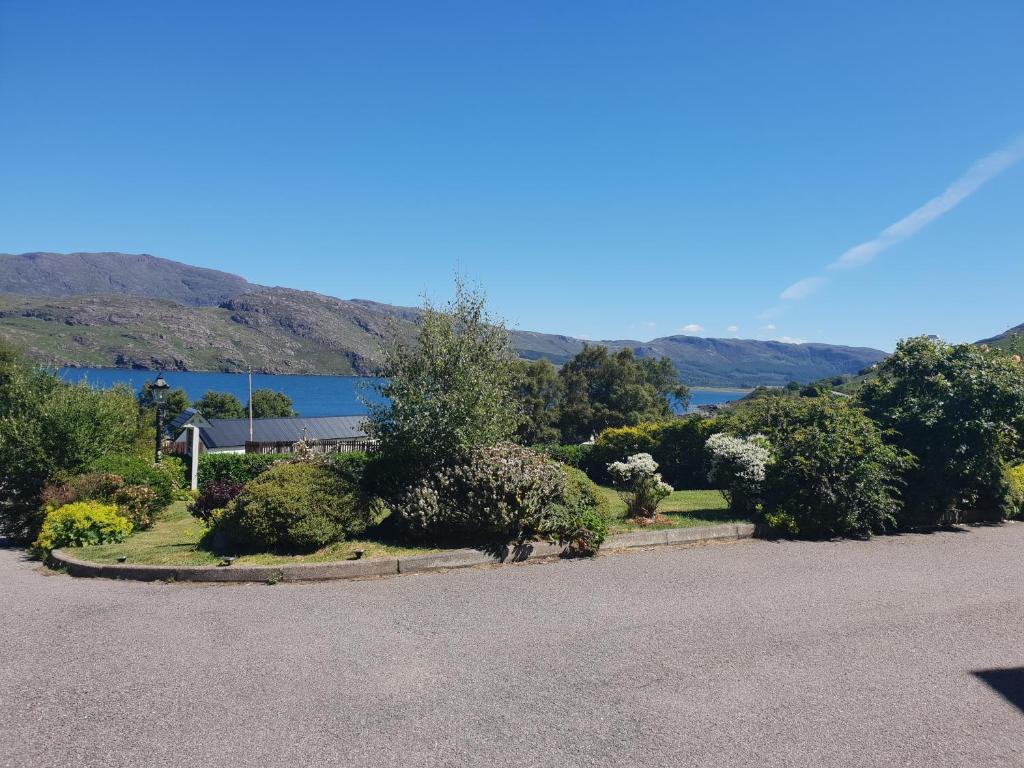 a parking lot with bushes and trees and a lake at Creag-Ard Bed & Breakfast in Dundonnell