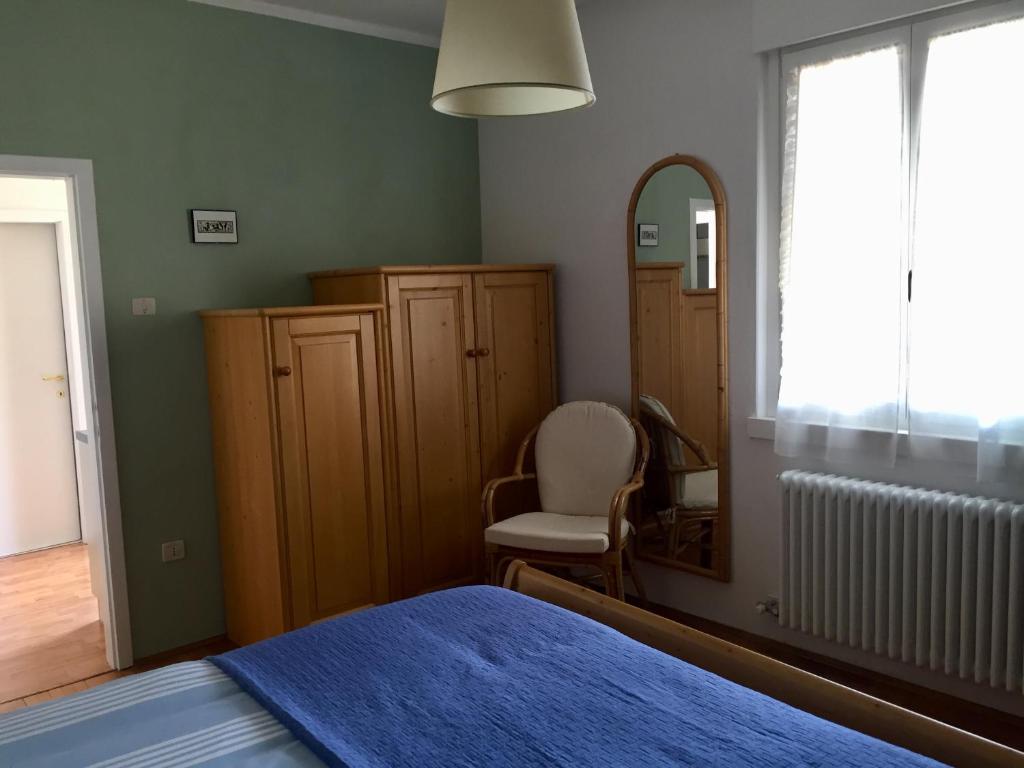 - une chambre avec un lit, un miroir et une chaise dans l'établissement Appartamento Guccio, à Caldonazzo