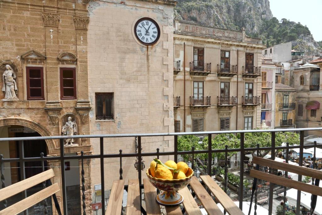 un bol de fruta en una mesa frente a una torre del reloj en Garibaldi B&B, en Cefalú
