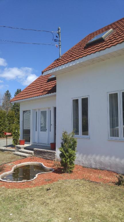 una casa blanca con un pequeño estanque en el patio en La Maison du Village, en Shawinigan