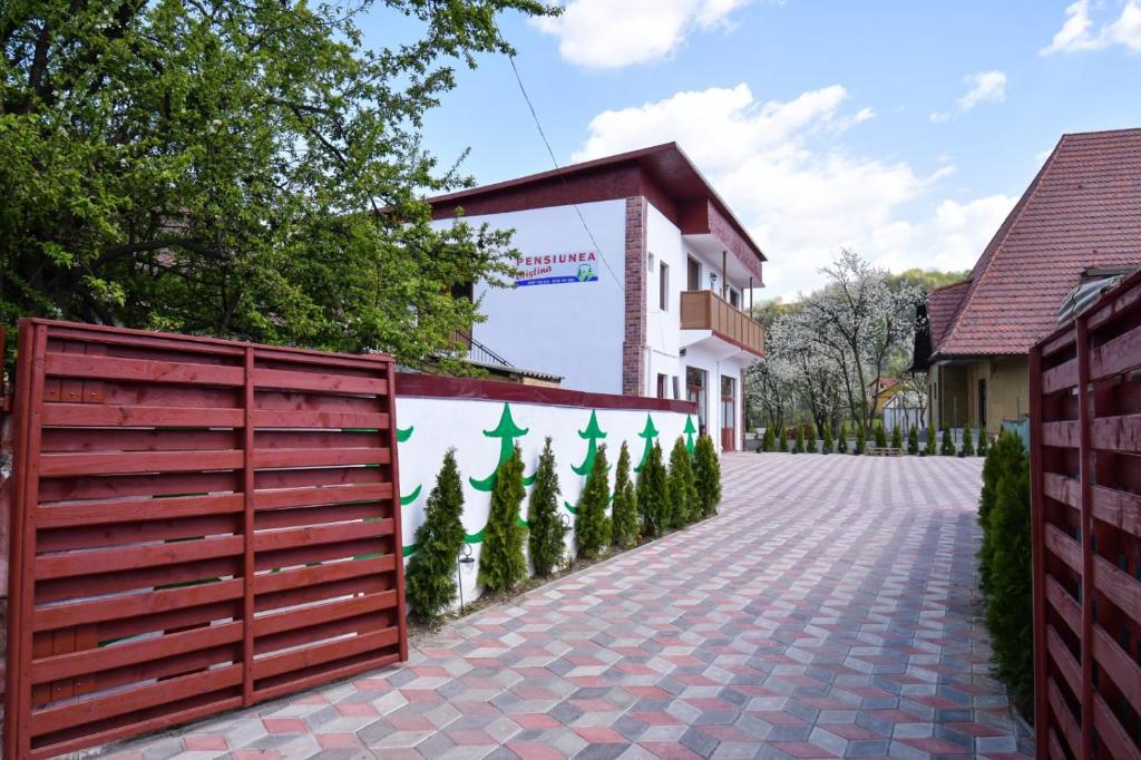 uma cerca com árvores em frente a um edifício em Pensiunea Cristina em Vişeu de Sus