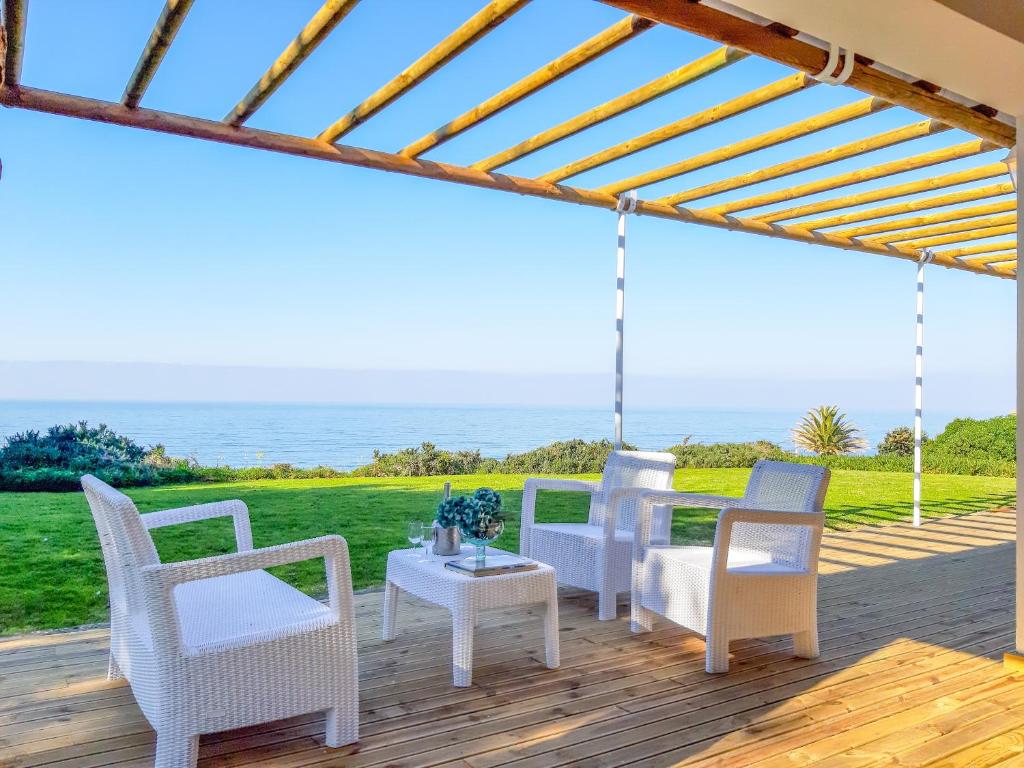 シントラにあるThe Beachfront Casa da Rampa IIの海の景色を望むパティオ(椅子、テーブル付)