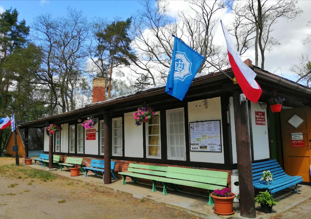 a building with benches and flags in front of it at POLICYJNY OŚRODEK WYPOCZYNKOWY in Niesulice