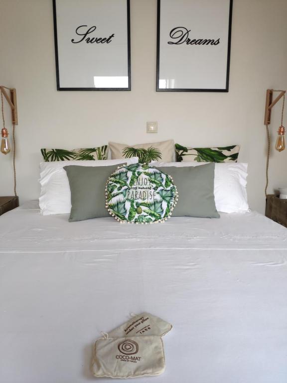 a white bed with a pineapple pillow on it at Olive Tree Cottage 2 in Nea Peramos