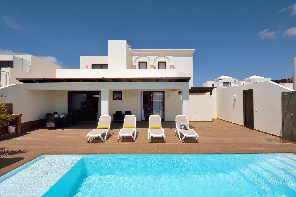 eine Villa mit einem Pool und 2 Gartenstühlen in der Unterkunft Villa Victoria in Playa Blanca