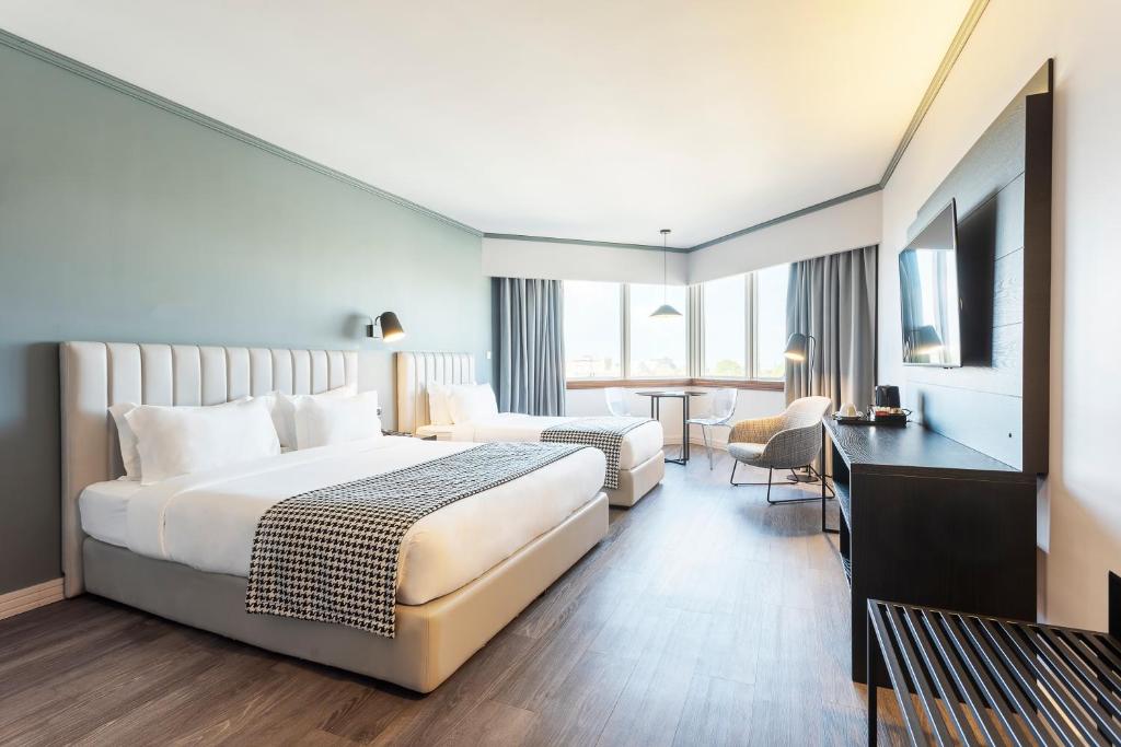 a hotel room with a bed, chair, and nightstand at HF Fenix Porto in Porto