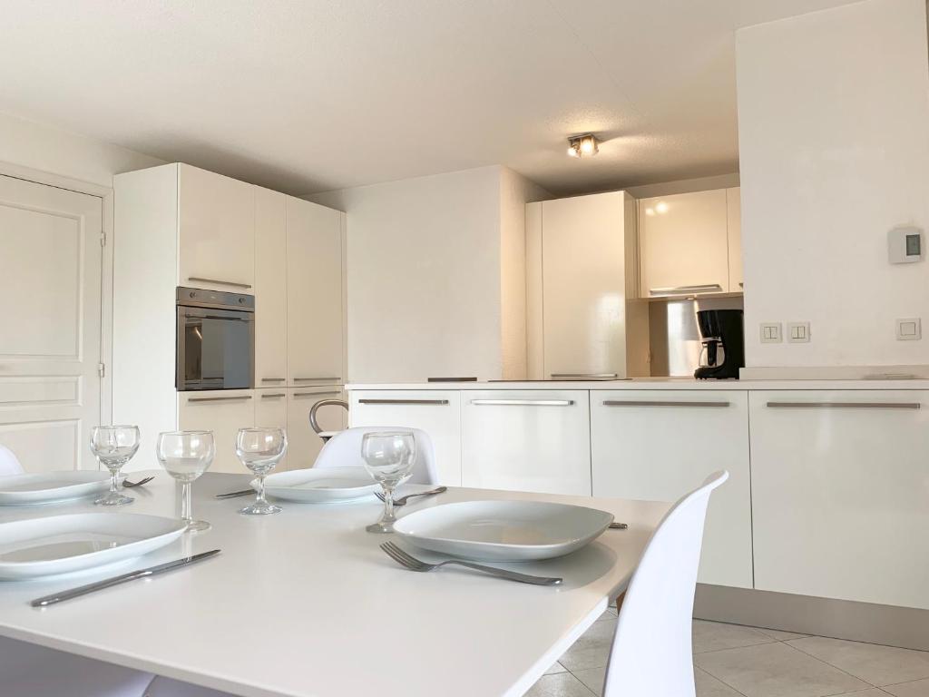 eine weiße Küche mit einem weißen Tisch und Stühlen in der Unterkunft Résidence Panoramer in Cannes