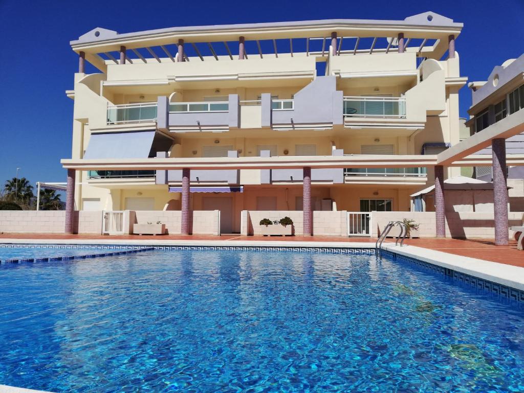a building with a swimming pool in front of a building at Mediterránea Solo Familias Serviplaya in Playa de Xeraco
