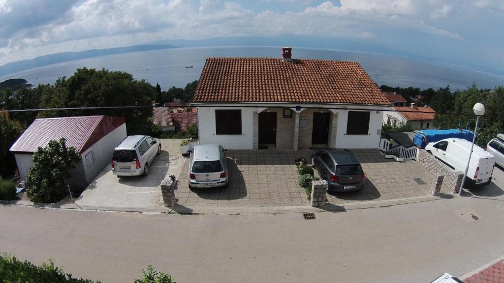 ein weißes Haus mit Autos auf einem Parkplatz in der Unterkunft Apartments Šudić in Njivice