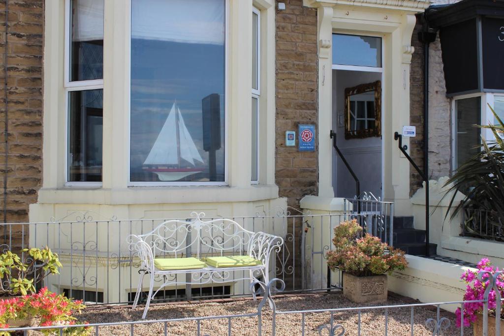 a white chair sitting outside of a house with a sailboat in the window at The Ashley in Morecambe