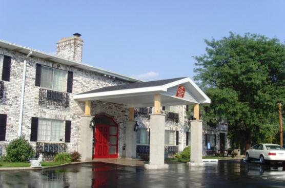 un edificio con una puerta roja en un aparcamiento en Ripon Welcome Inn and Suites, en Ripon