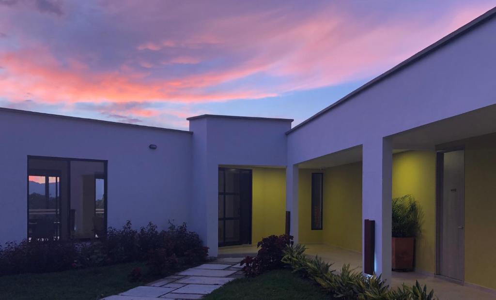 a white building with a sunset in the background at Hotel Boutique La Ceiba in Quimbaya