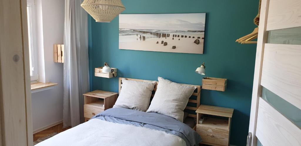 um quarto com uma cama com uma parede azul em Casa del Mare, Apartments and more em Leba
