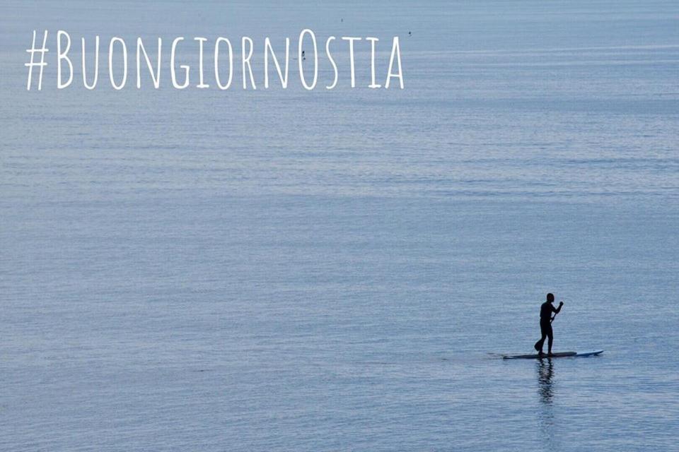 een man op een surfplank in het water bij Camping Internazionale Di Castelfusano in Lido di Ostia