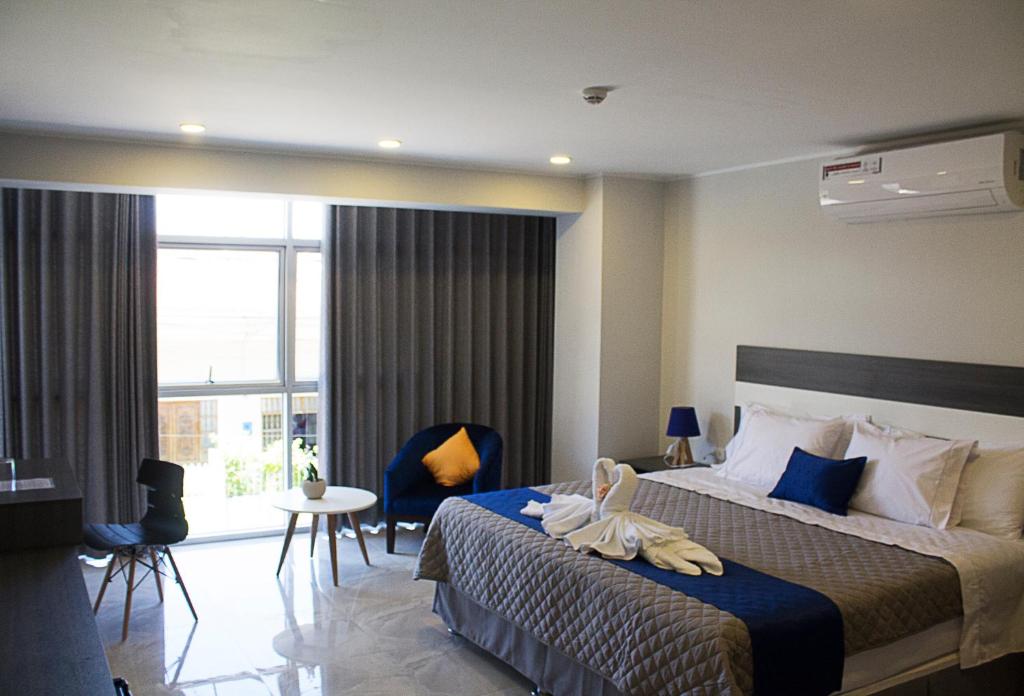 Palm Hotel Tarapoto في تارابوتو: غرفة فندقية بسرير ونافذة كبيرة