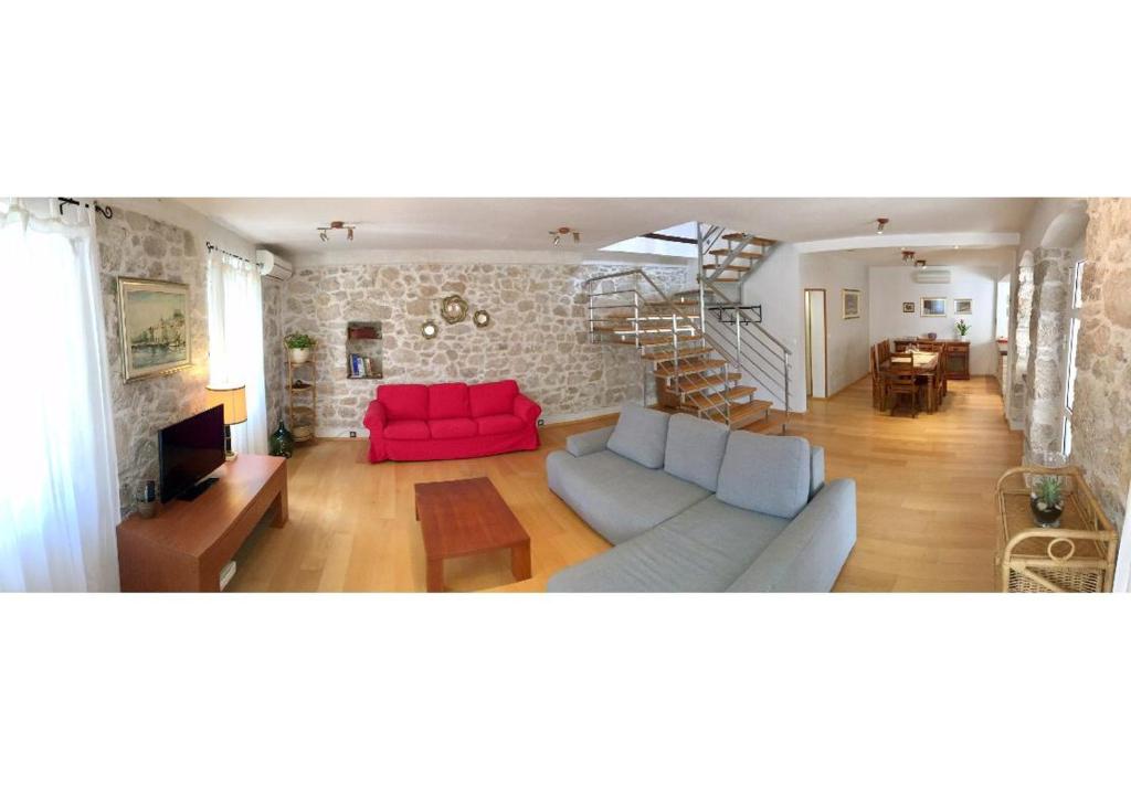 a living room with a red couch and a staircase at Apartman Belamaric in Šibenik