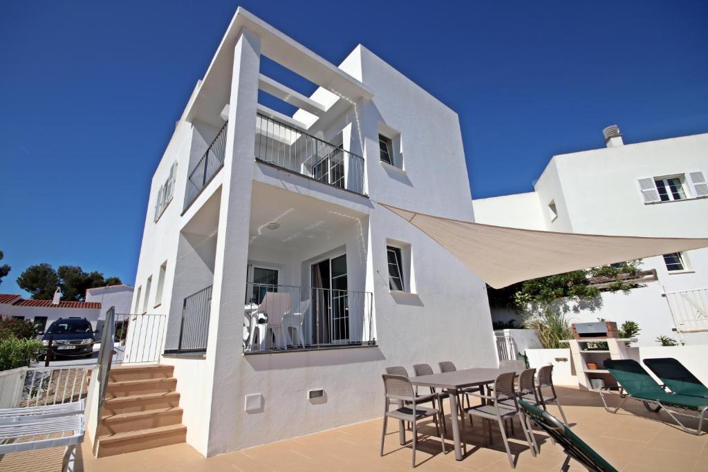 uma casa branca com uma mesa e cadeiras num pátio em Villa Can Bella, 350m zum Strand em Cala Galdana