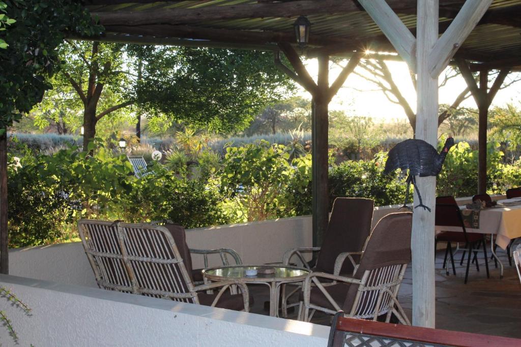 eine Terrasse mit Stühlen, Tischen und einem Sonnenschirm in der Unterkunft Etango Ranch Guest Farm in Voigtland