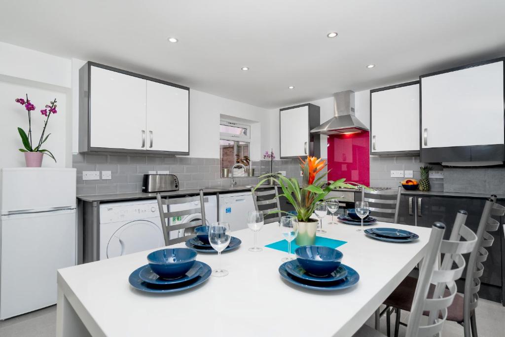 a white kitchen with a white table and chairs at Childs Hill Vacation Home in London