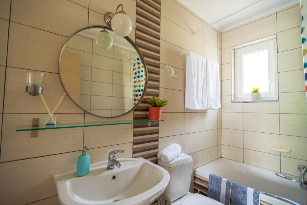 a bathroom with a sink and a mirror and a toilet at House Christie in Chrysi Ammoudia