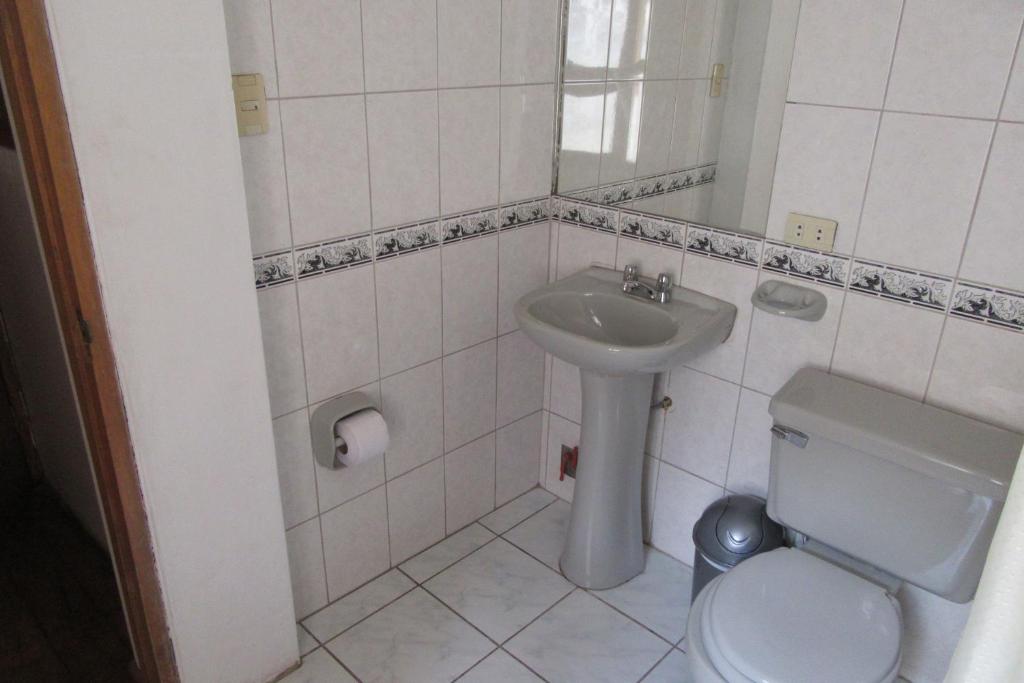 a white bathroom with a toilet and a sink at Hospedaje Kamila in Cusco