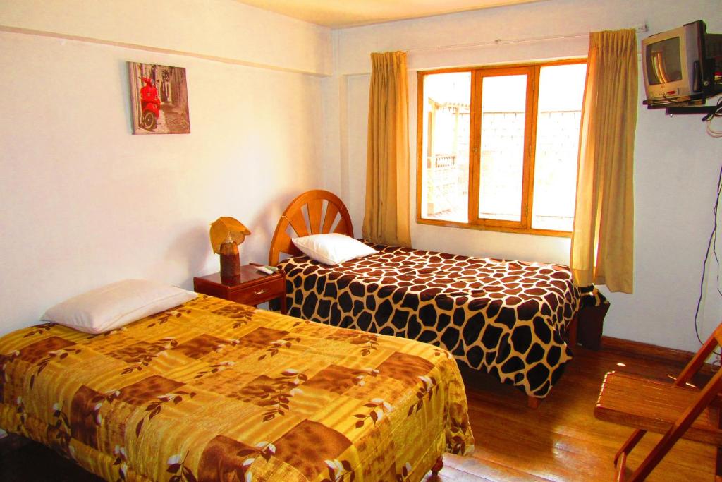 a hotel room with two beds and a window at Hospedaje Kamila in Cusco