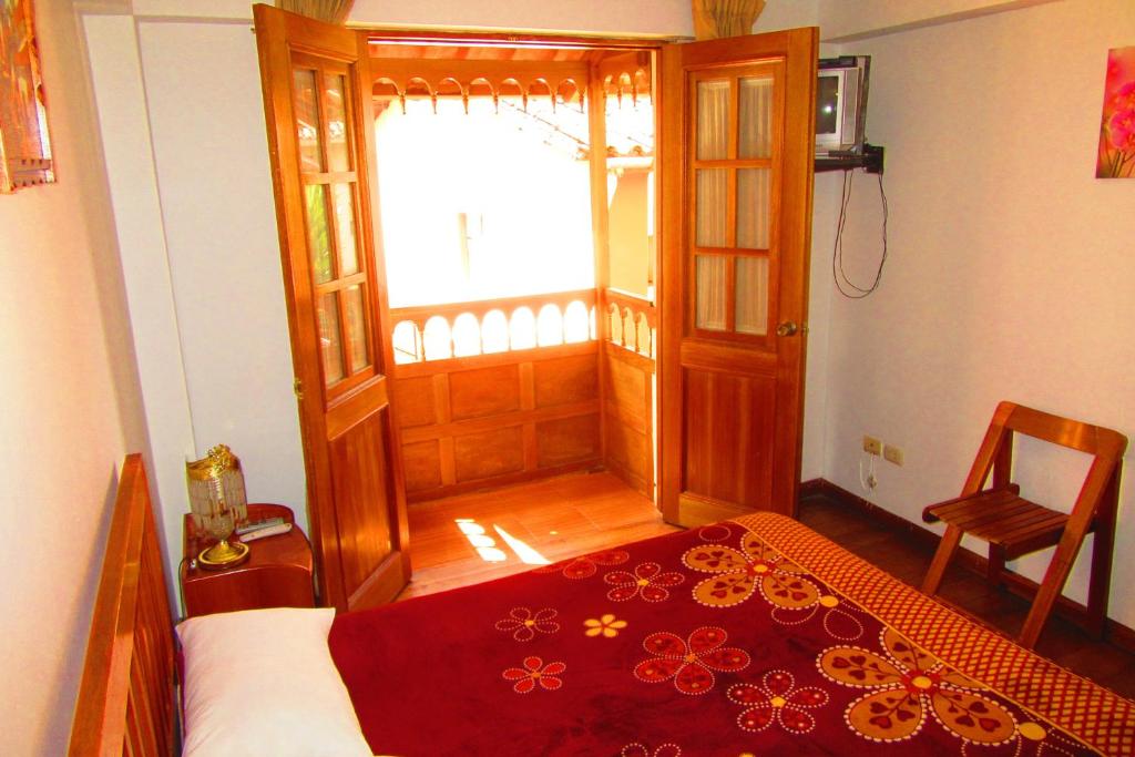 a bedroom with a bed with a red blanket on it at Hospedaje Kamila in Cusco