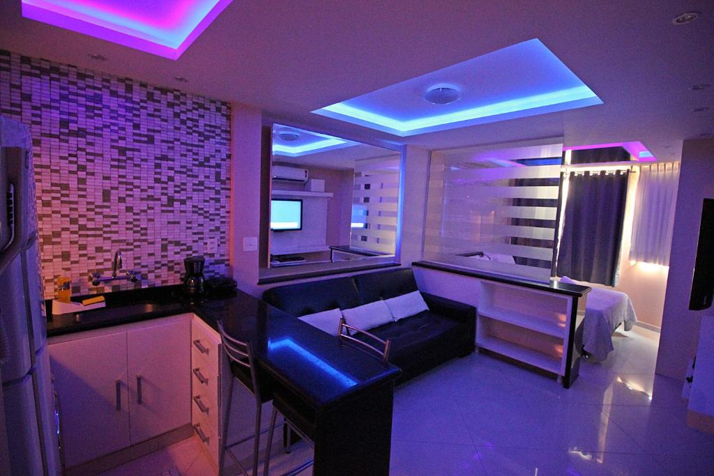 a living room with a couch and a kitchen with purple lights at Rio Spot Homes C046. in Rio de Janeiro