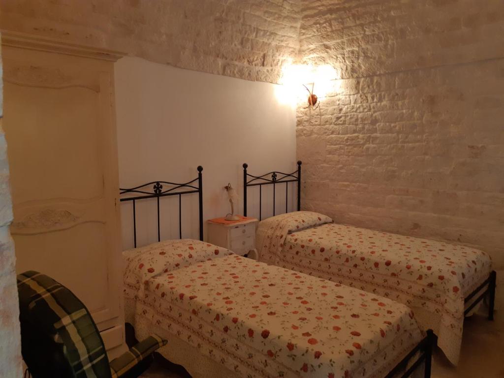 アルベロベッロにあるAlberobello Casa Vacanze - Pathos tra i Trulliのレンガの壁、ベッド2台が備わるベッドルーム1室が備わります。