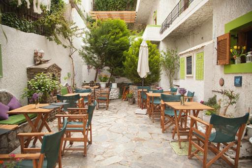 patio ze stołami, krzesłami i parasolem w obiekcie Gioma Hotel w mieście Agia Galini