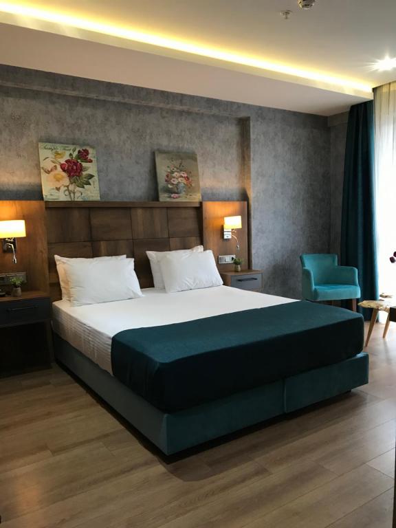 a bedroom with a large bed and a blue chair at Dedehan Hotel in Trabzon