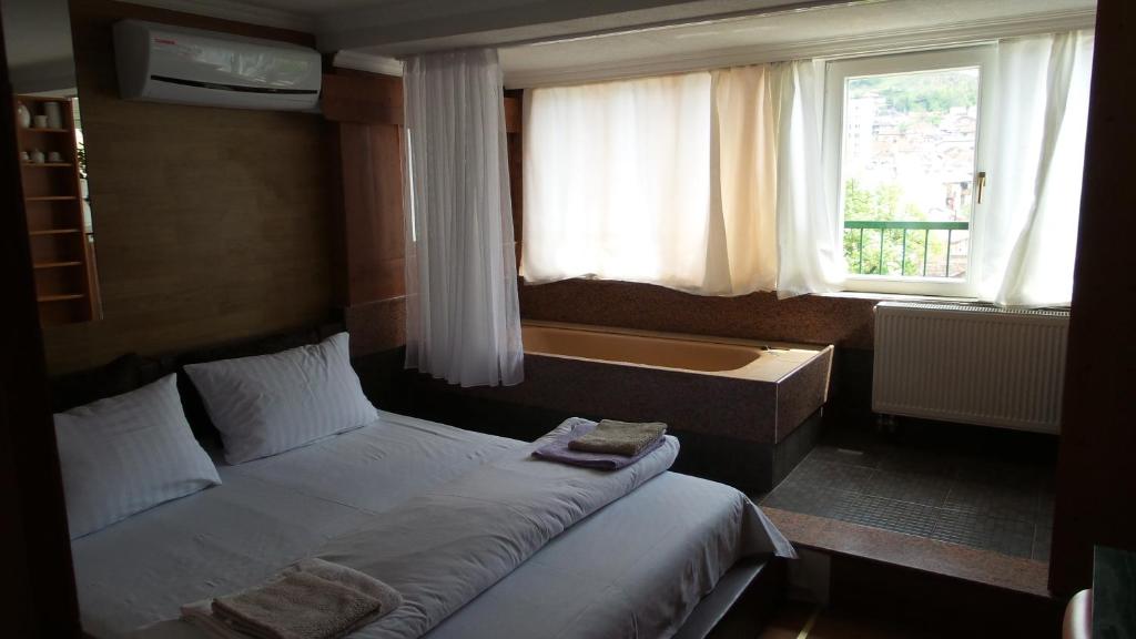 een slaapkamer met een bed en een bad in een raam bij Apartments Emily in Sarajevo