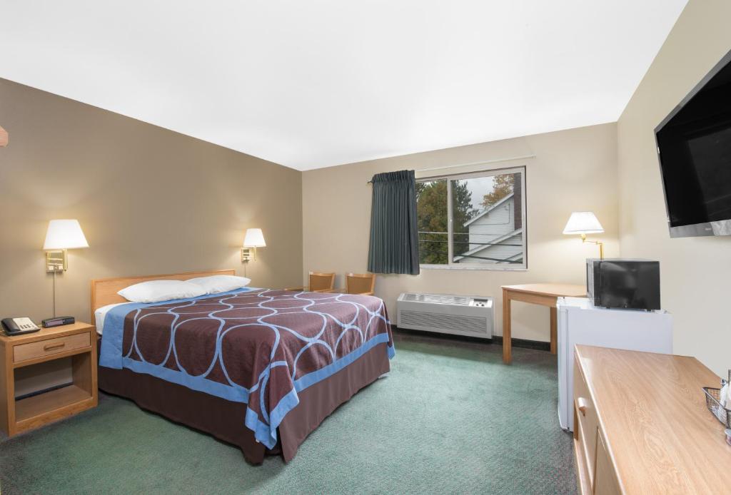 ElyにあるNorthwoods Inn and Suitesのベッド1台、薄型テレビが備わるホテルルームです。