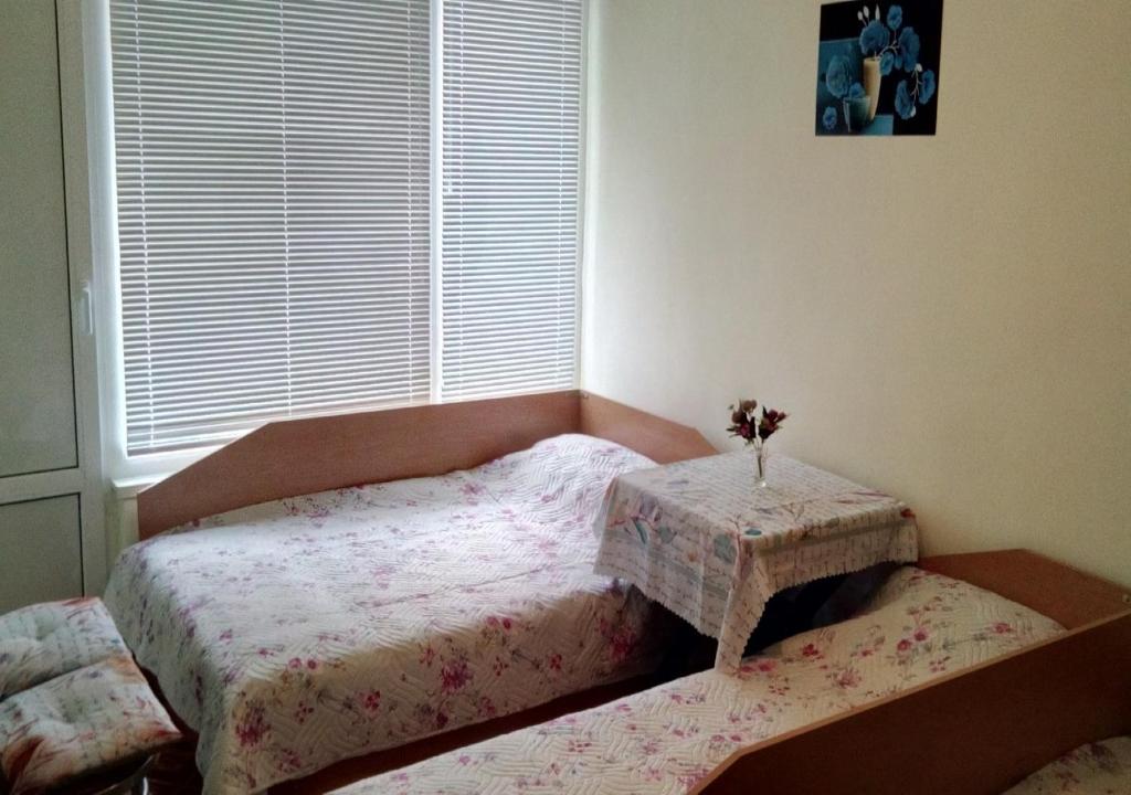 a bedroom with two beds and a table in front of a window at Апартамент Флора - гр.Приморско ММЦ in Primorsko