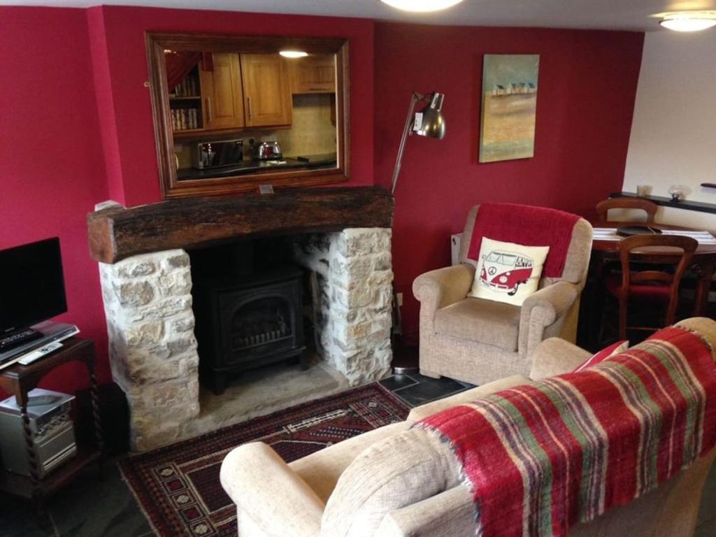 a living room with a stone fireplace and two chairs at Causeway Cottage in Cartmel