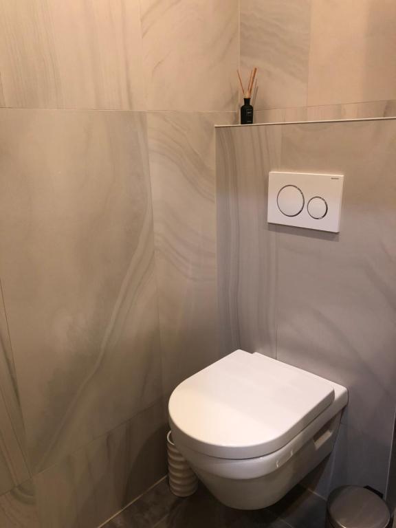 een badkamer met een toilet en 2 klokken aan de muur bij Cintra in Middelkerke