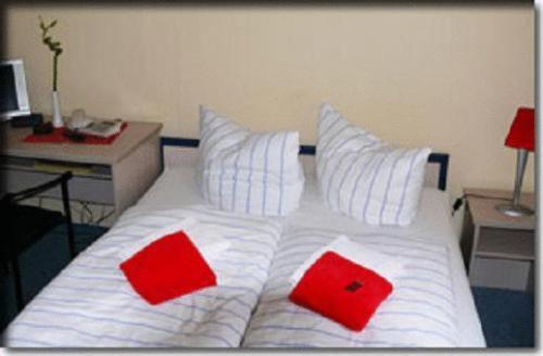 a white bed with two red pillows on it at Mecklenburger Hof in Mirow