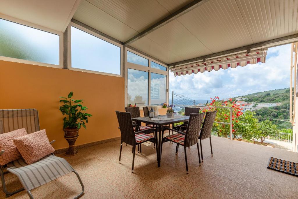 a dining room with a table and chairs and windows at Apartments Daniela in Zavalatica